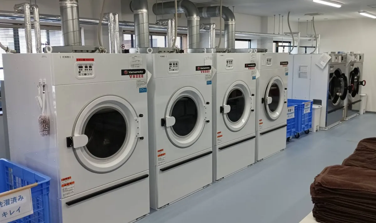 設置が完了し、排気ダクトにつながった業務用乾燥機と洗濯機