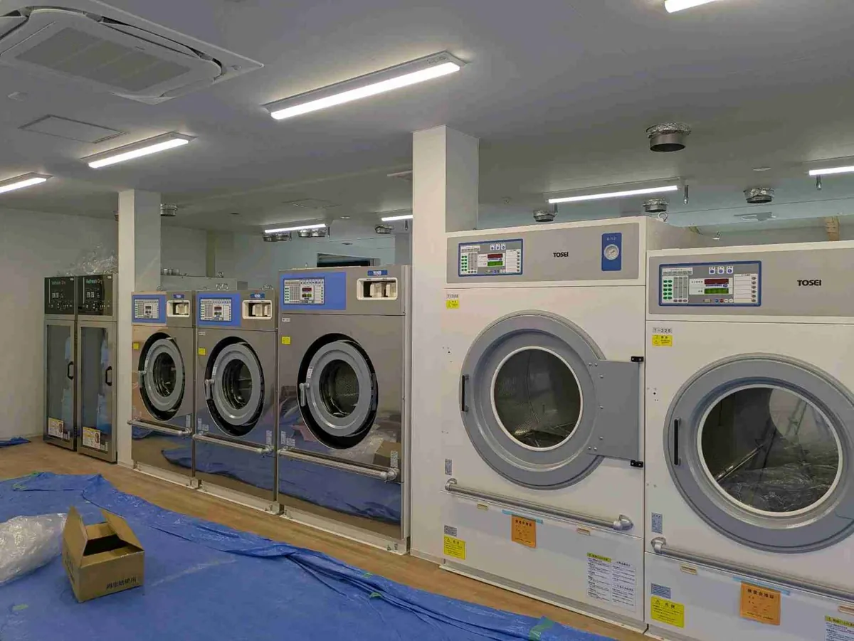 床を養生した状態で搬入された業務用洗濯機と乾燥機